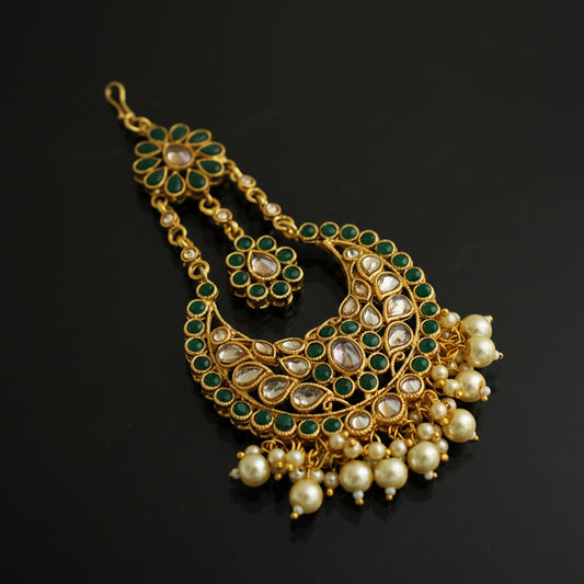 Gold necklace with green and pearl accents on a black background