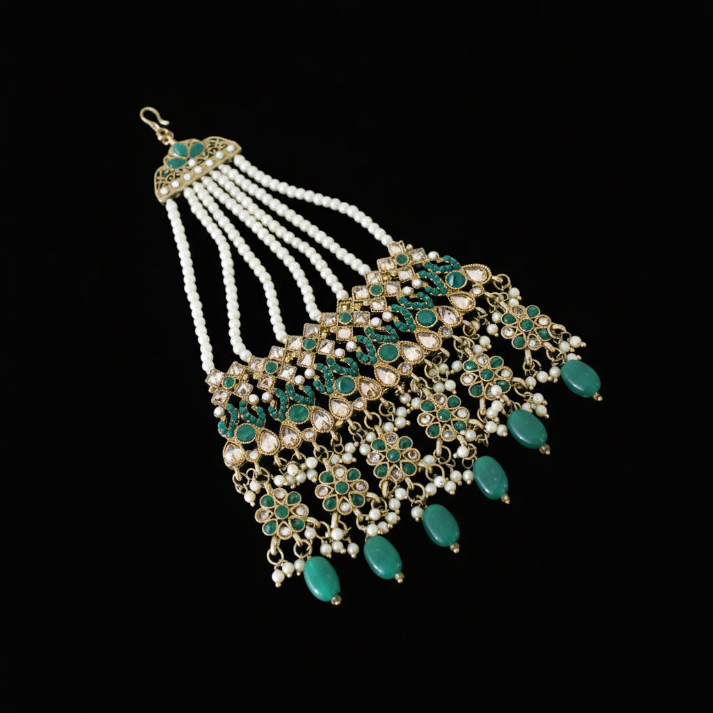 Ornate necklace with green and gold details on a dark background, featuring the brand 'Saheli'.