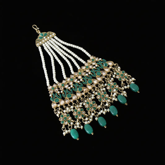 Ornate necklace with green and gold details on a dark background, featuring the brand 'Saheli'.