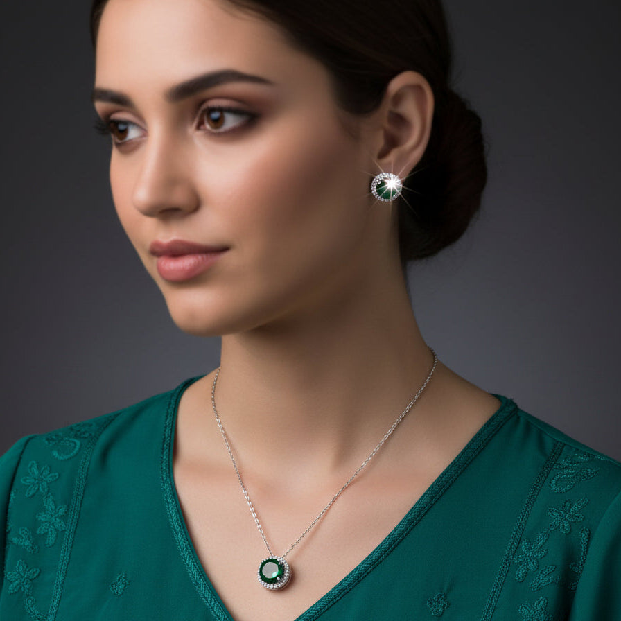 Jewelry set with necklace and earrings featuring green gemstones on a black background, branded 'Saheli'.