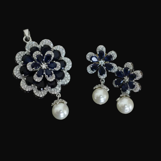 Floral earrings with blue and pearl details on a dark background, featuring the brand 'Saheli'.