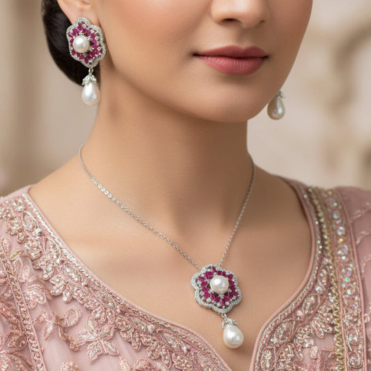 Jewelry set with pink gemstones and pearl drops on a dark background, featuring the brand 'Saheli'.