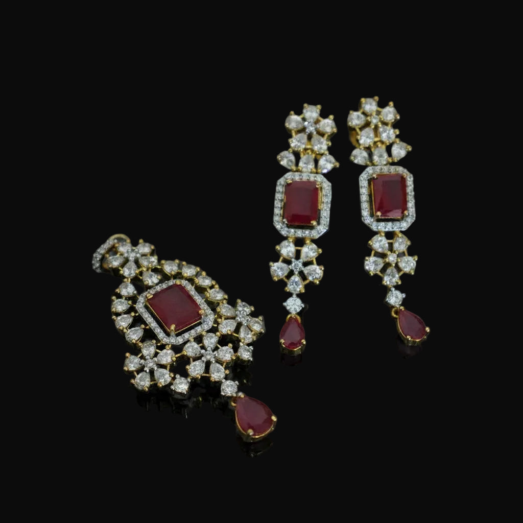 Pair of ornate earrings with red gemstones and gold accents on a dark background, branded 'Saheili'.
