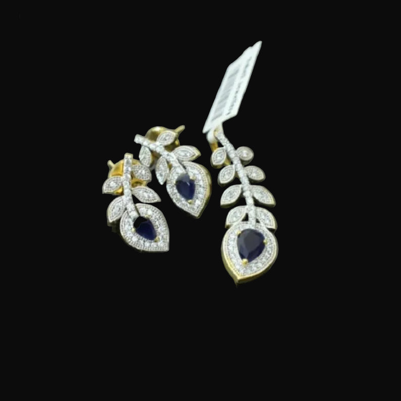 Pair of diamond earrings with blue gemstones on a gray background, featuring the brand 'Saheli'.