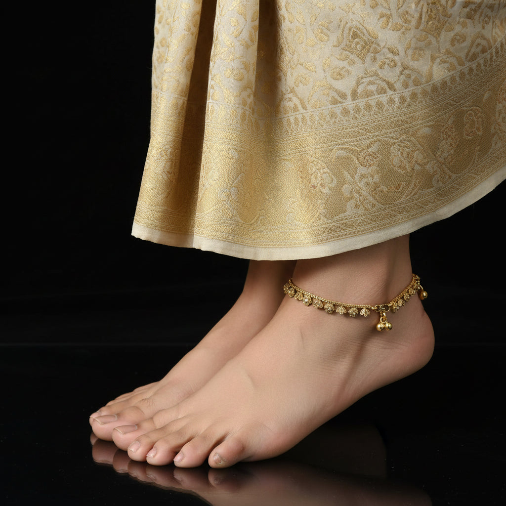 Gold anklet on a foot with a patterned skirt against a black background