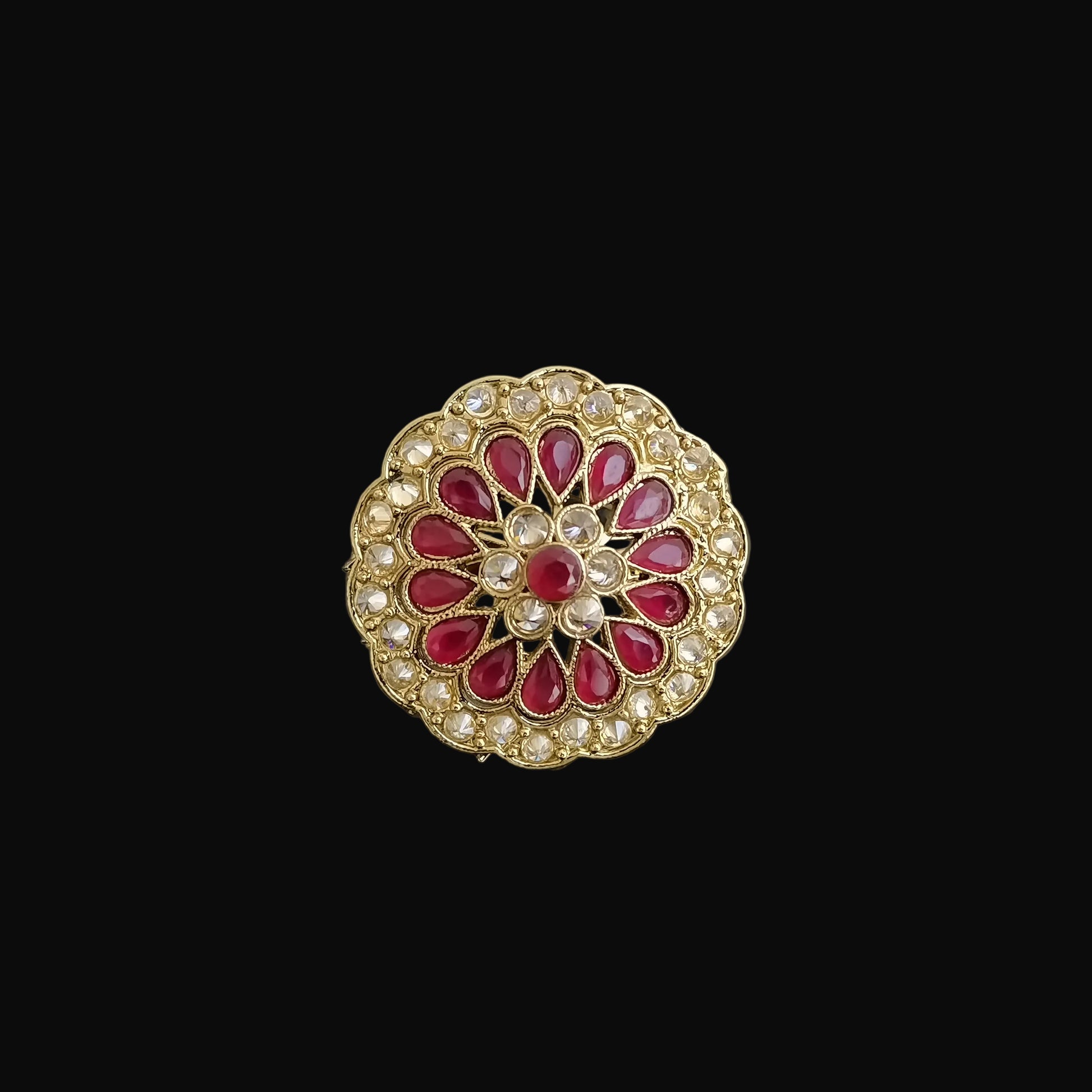 Decorative brooch with red gemstones and gold accents on a dark background