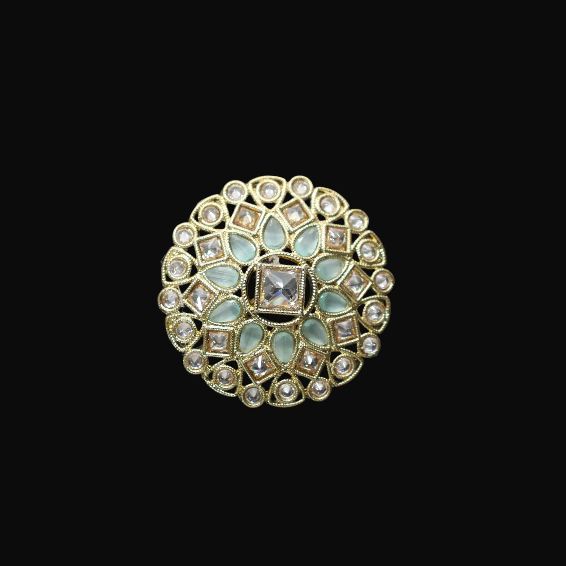 Decorative ring with gemstones on a black mannequin hand against a dark background