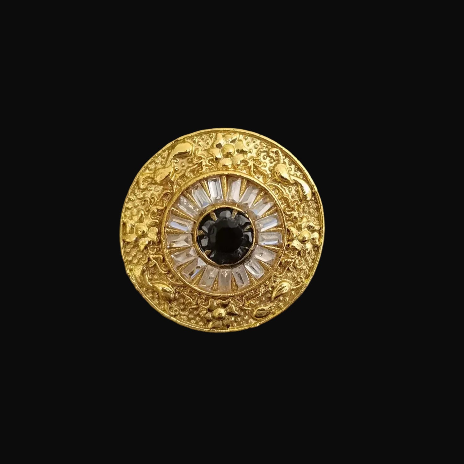 Gold brooch with central gemstone on a gray background, featuring the brand 'Saheli'.