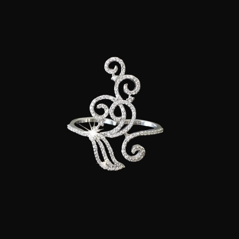 Silver ring with intricate design on a black background