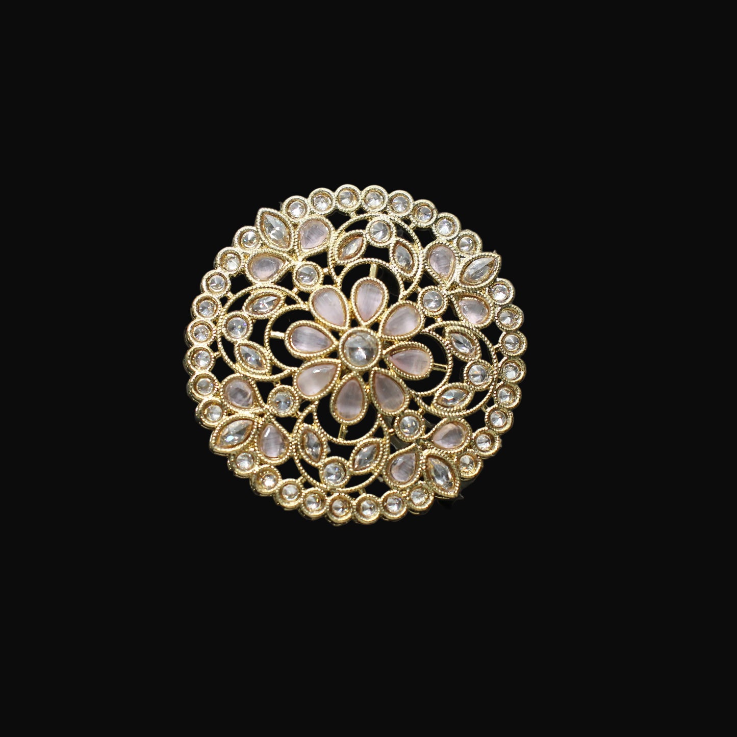Gold ring with intricate design on a black mannequin hand against a dark background