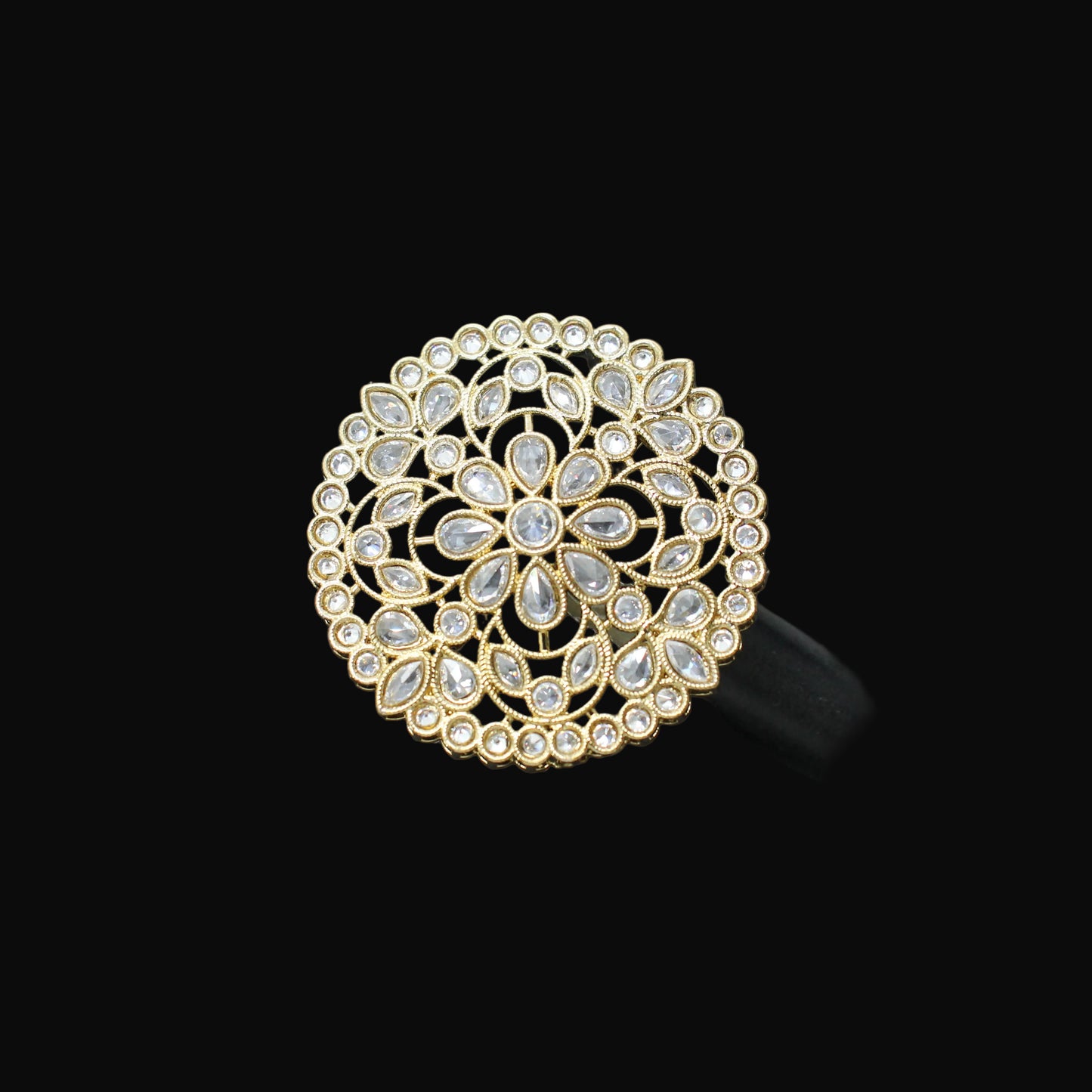 Gold and crystal brooch on a black mannequin hand against a dark background