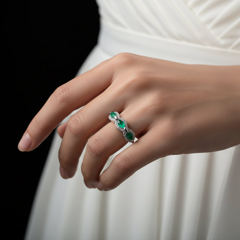 Silver ring with green gemstones on a black hand model, featuring the brand 'Saheli'.