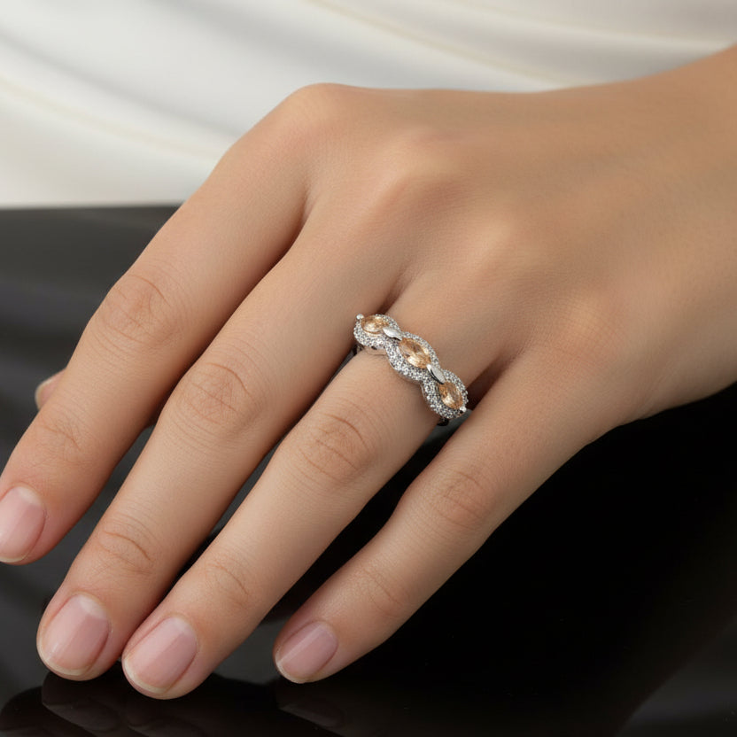 Silver ring with brown stones on a black gloved hand, brand 'SAHELI' visible.