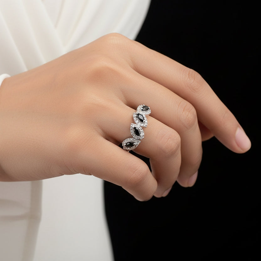 Silver ring with black stones on a gray background, featuring the brand 'SAHELLI'.
