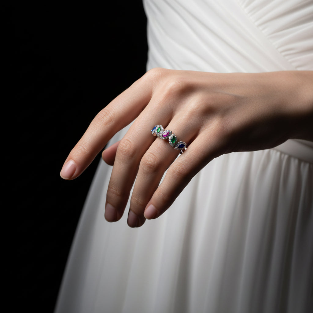 Silver ring with colored gemstones on a gray background, featuring the brand 'SAHELLI'.