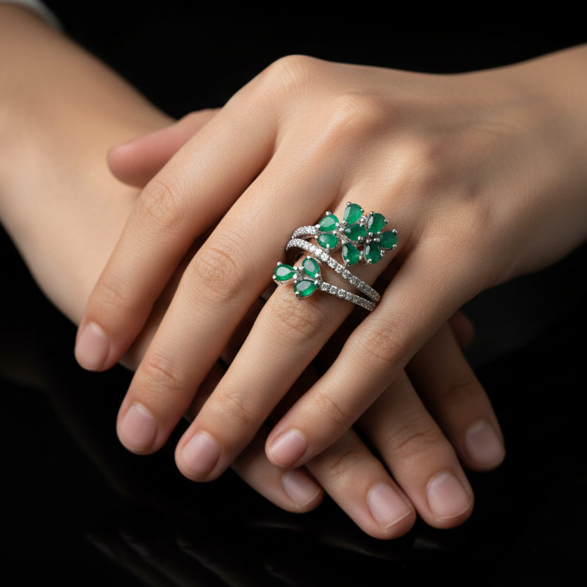 Silver ring with green gemstones on a gray background, featuring the brand 'Saheli'.