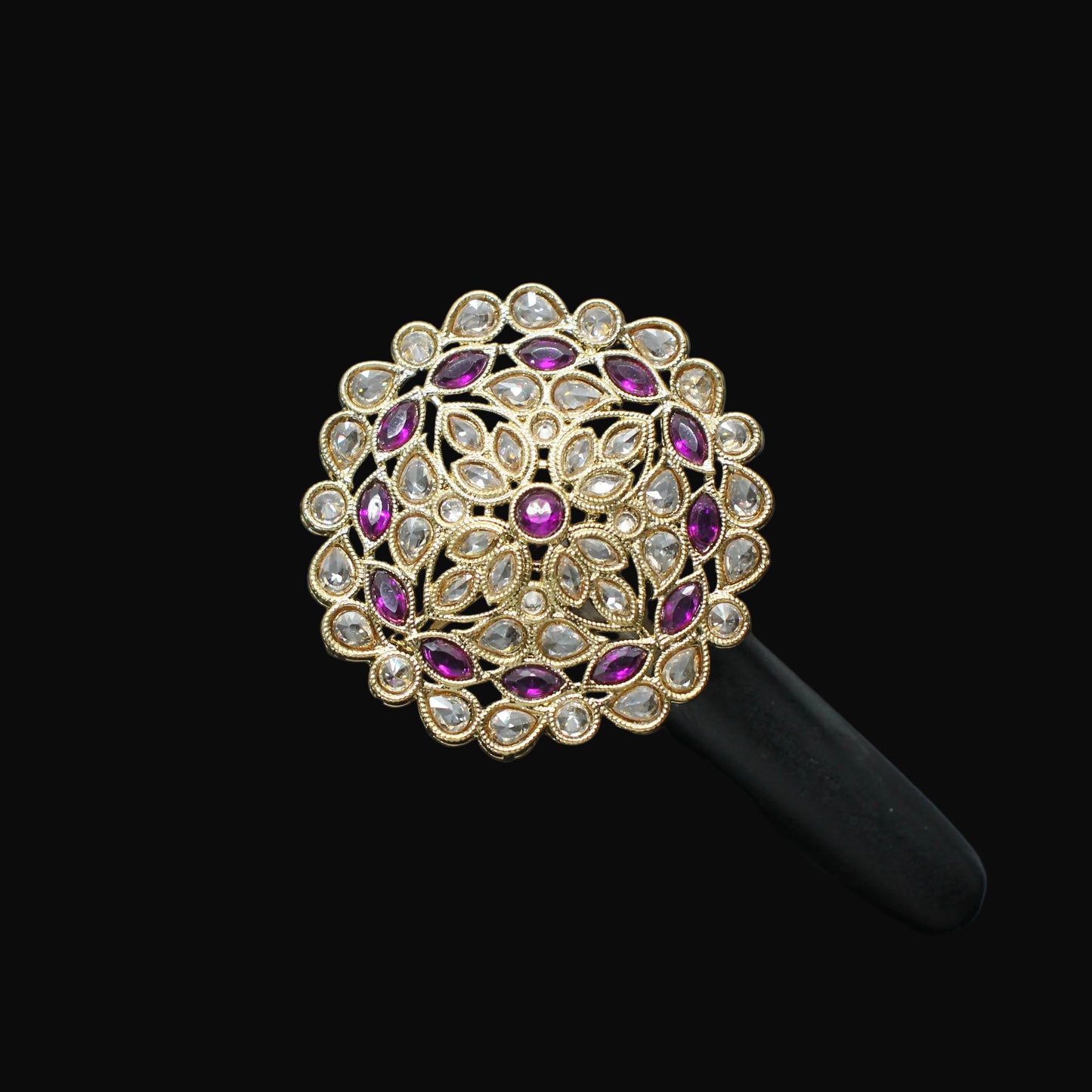 Decorative ring with purple stones on a black mannequin hand against a dark background