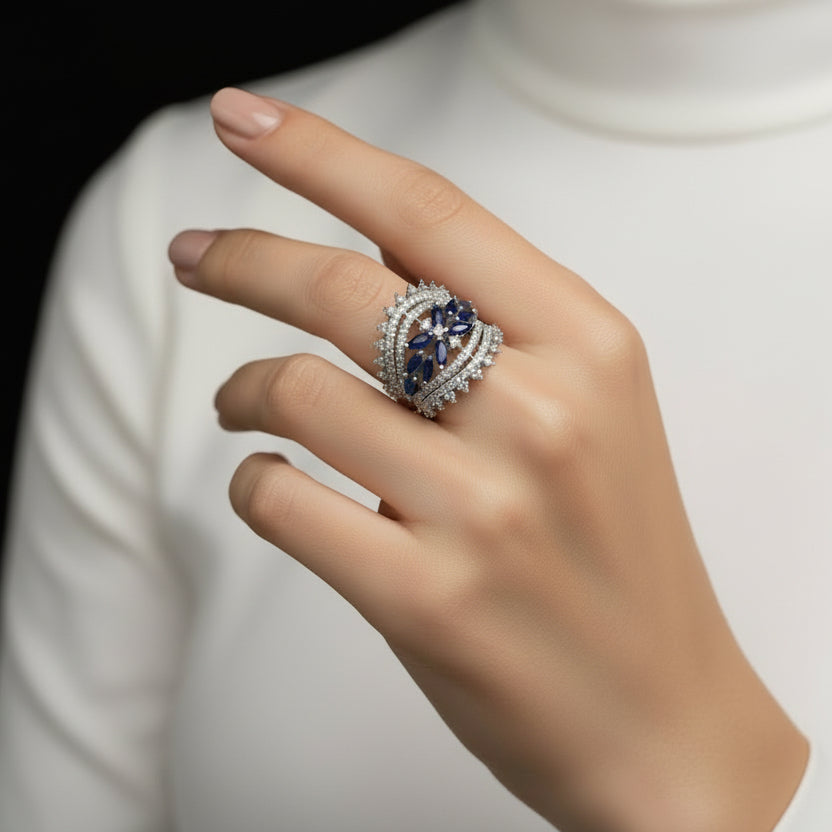 Silver ring with blue gemstones on a gray background, featuring the brand 'Saheli'.