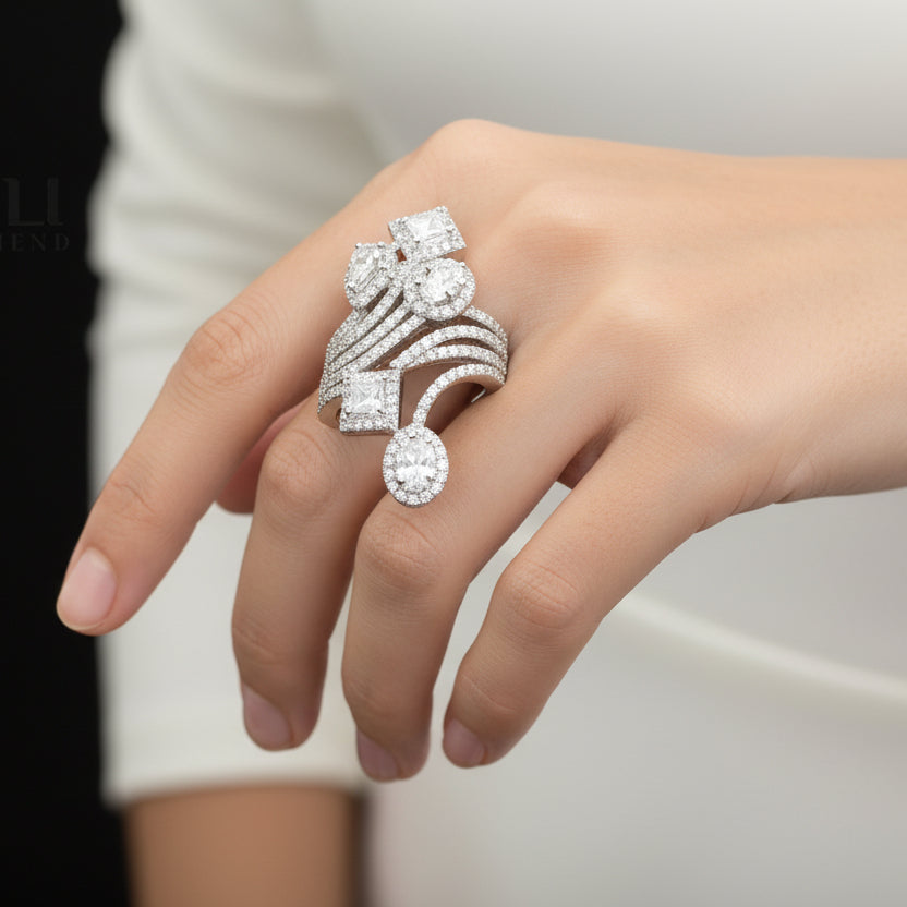 Silver ring with gemstones on a gray background, featuring the brand 'Saheli'.