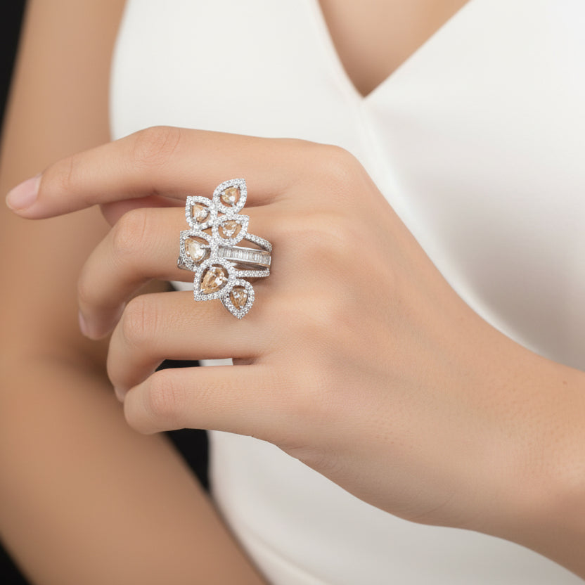 Silver ring with gemstones on a gray background, featuring the brand 'Saheli'.