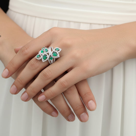 Silver ring with green gemstones on a gray background, featuring the brand 'Saheli'.