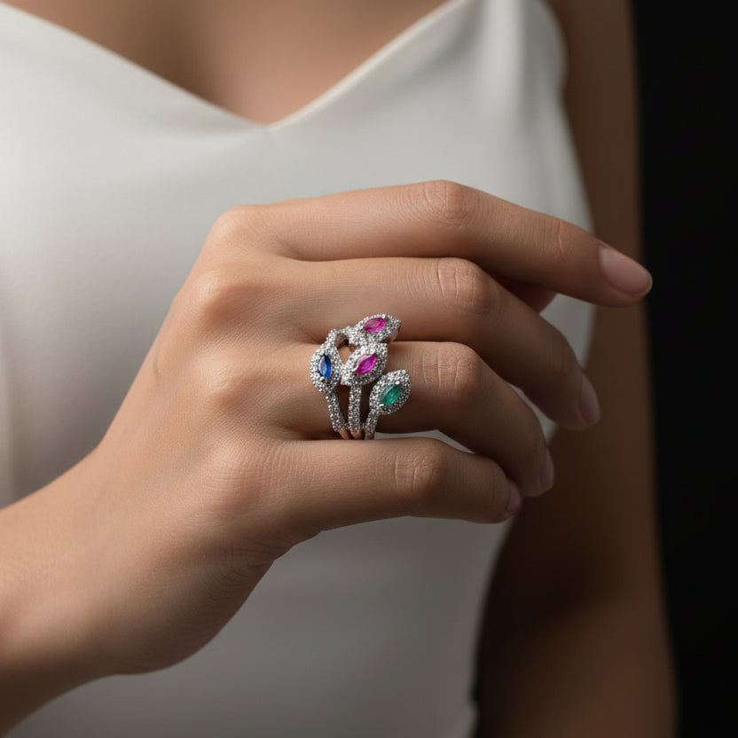 Silver ring with colorful gemstones on a gray background, featuring the brand 'SAHELI'.