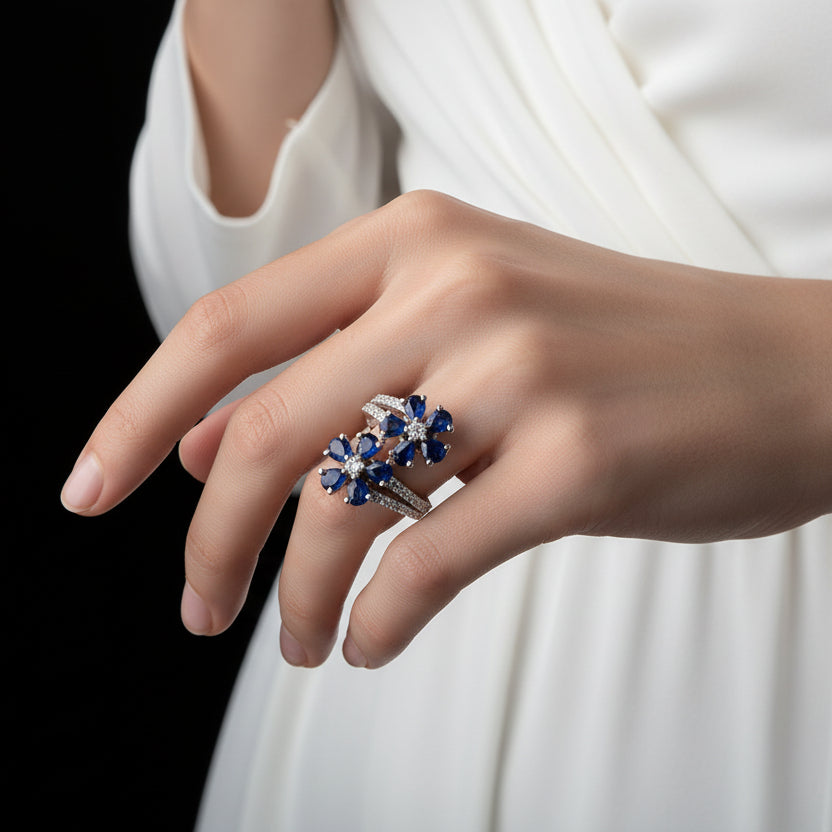 Silver ring with blue gemstones on a black mannequin hand, featuring the brand 'Saheli'.