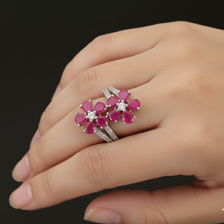 Silver ring with pink gemstones on a hand against a dark background