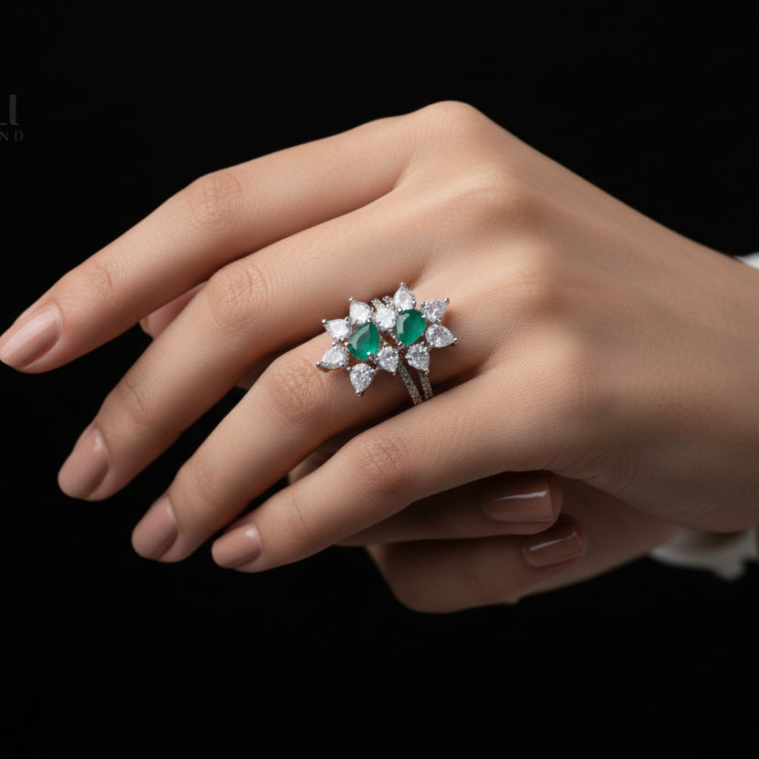 Silver ring with green gemstones on a dark background, featuring the brand 'Saheili'.
