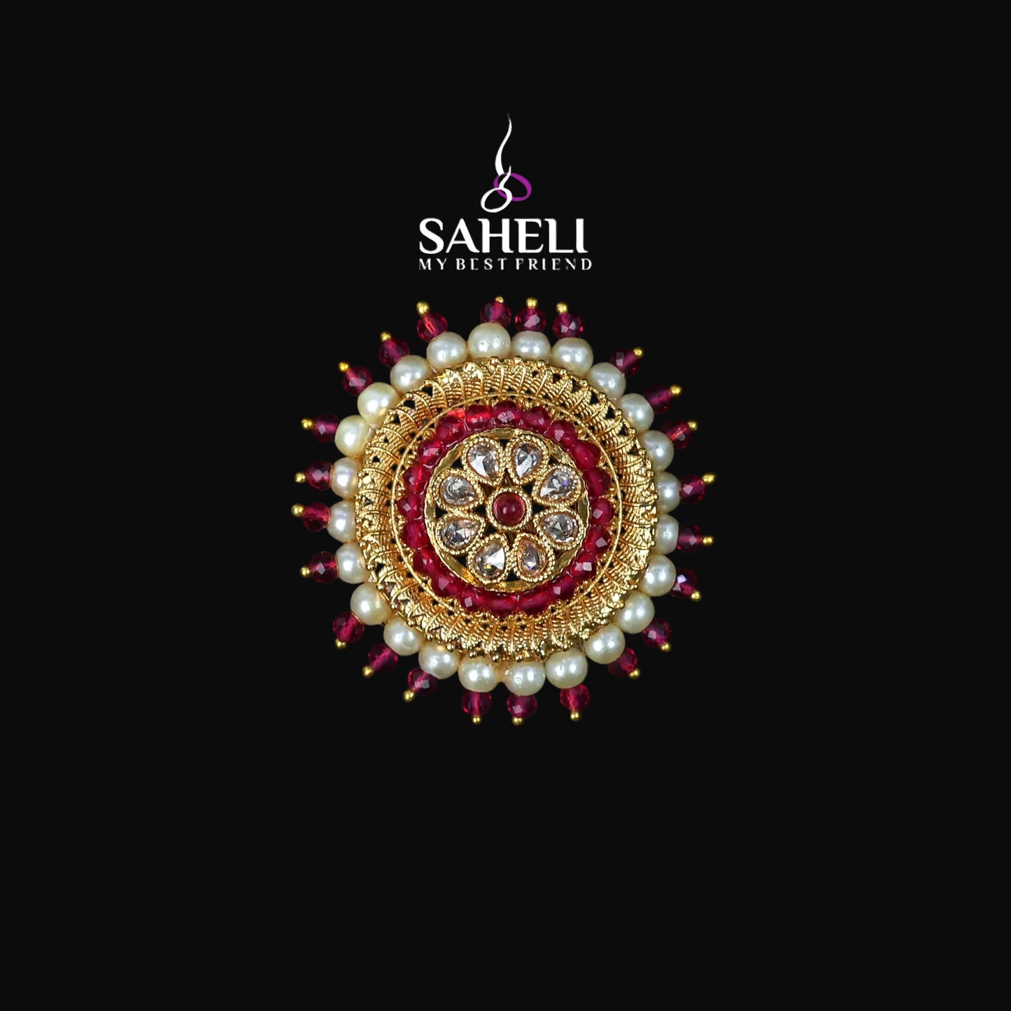 Decorative brooch with pearls and red stones on a black background, featuring the brand 'Saheli'.