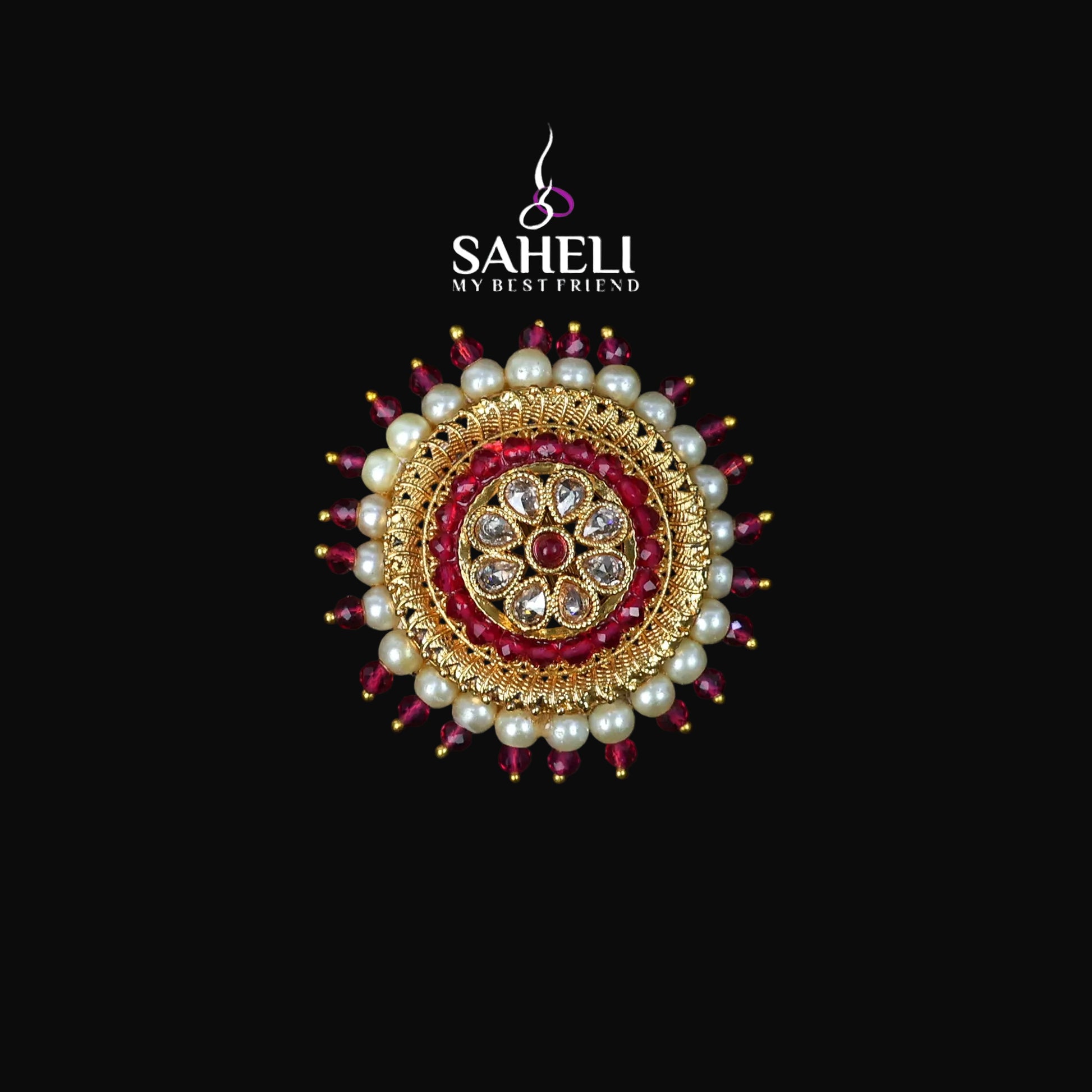 Decorative brooch with pearls and red stones on a black background, featuring the brand 'Saheli'.