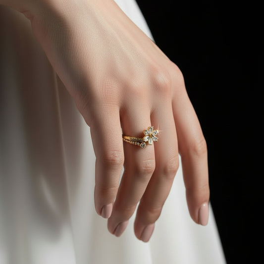 Gold ring with a floral design on a black mannequin hand against a gray background