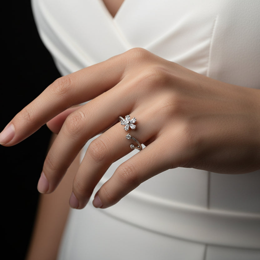Silver ring with a floral design on a black mannequin hand against a gray background