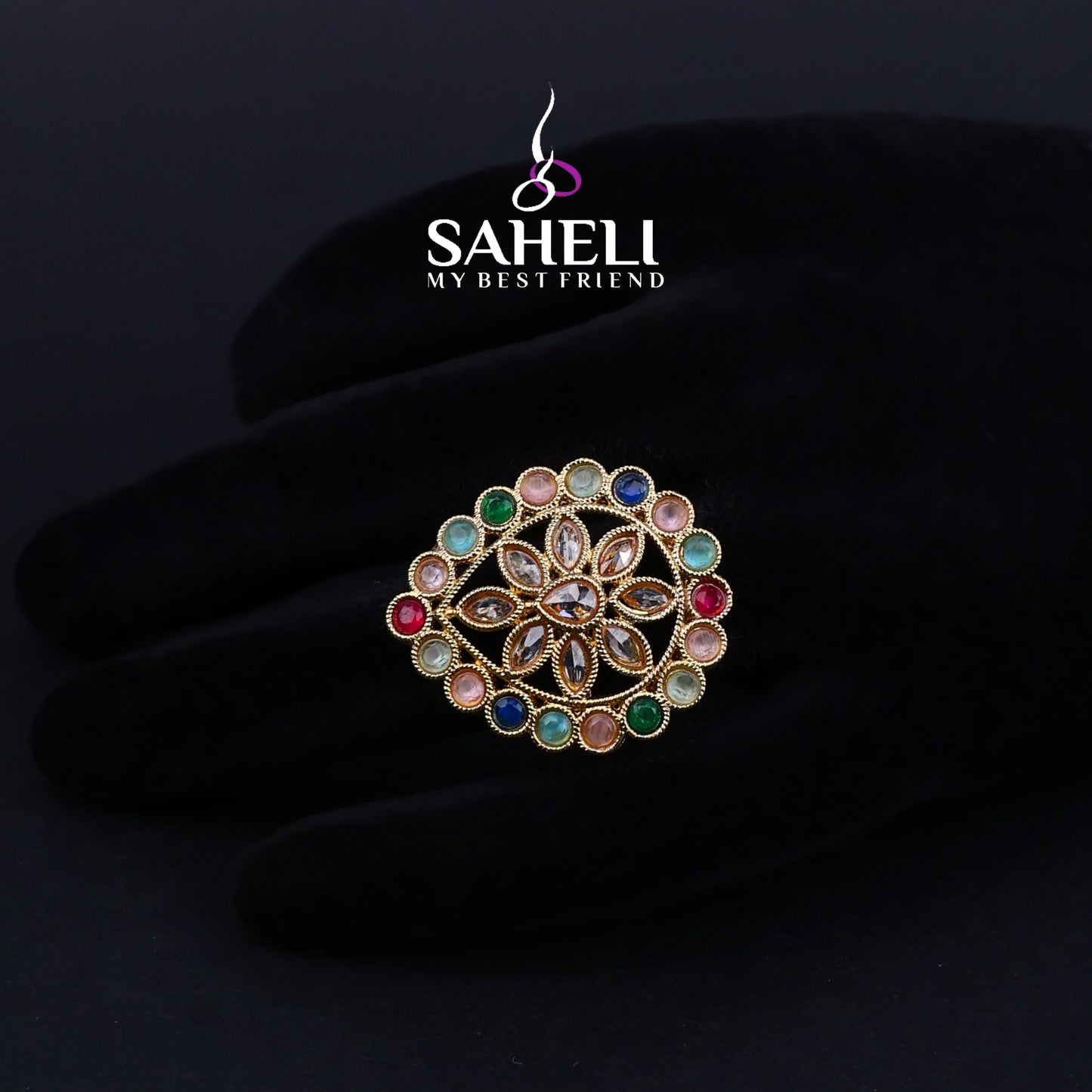 Multicolored gemstone brooch on a dark background with 'Saheli' brand logo.