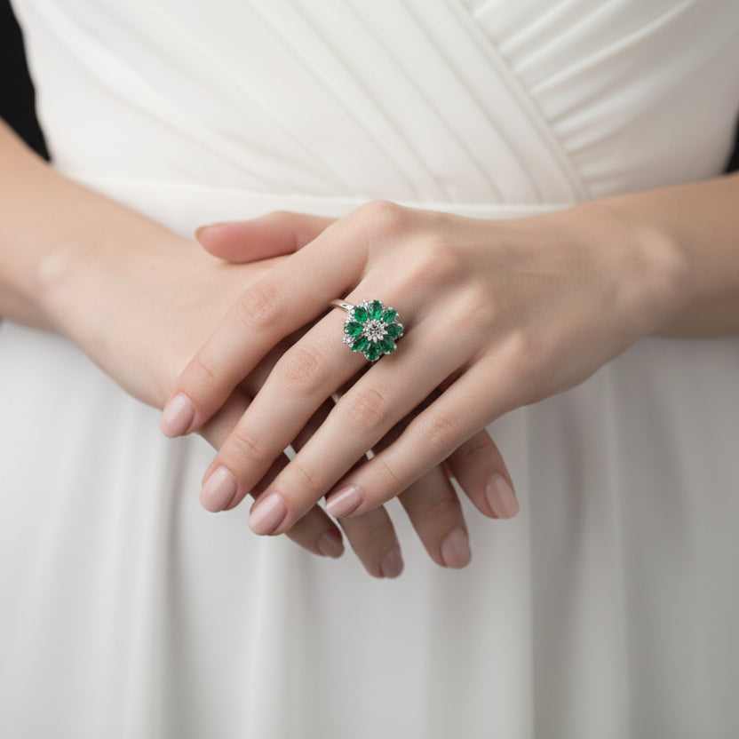 Green emerald ring on a black mannequin hand against a gray background