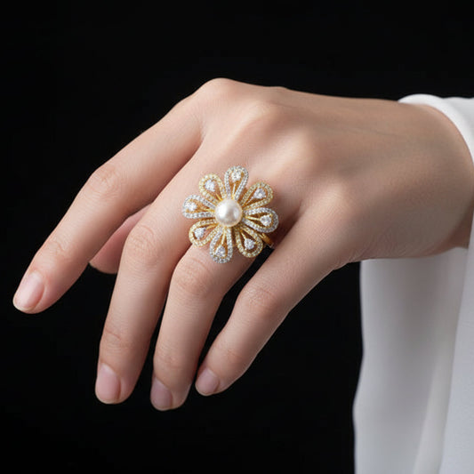 Gold flower-shaped ring with a pearl center on a black mannequin hand.