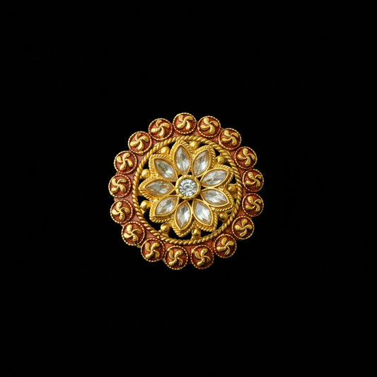 A circular gold-toned ornamental brooch or decorative pin with a floral center and a border of small red and gold motifs, shown on a dark gray background. The brand name 'SAHELL MY BEST FRIEND' is visible in the upper left corner.