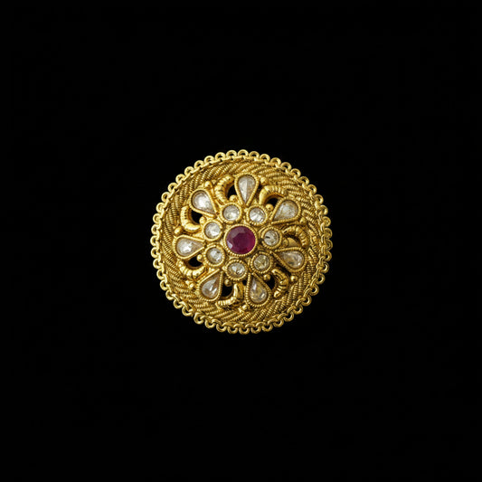 An ornate circular gold-toned brooch or decorative pin featuring a central red gemstone surrounded by clear stones in a floral mandala pattern, displayed on a dark gray background with a 'SAHELL MY BEST FRIEND' watermark in the top right.