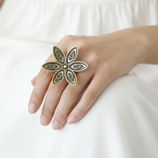 Gold floral ring on a black mannequin hand with 'SAHELI' branding.