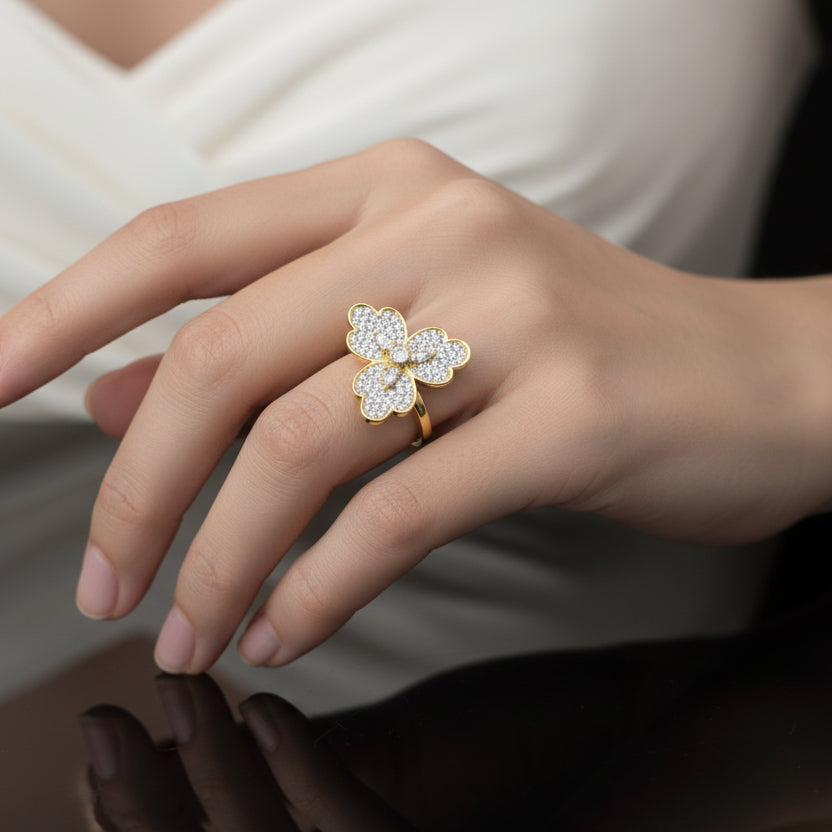 Gold and diamond flower-shaped ring on a gray background with 'SAHELI' branding.