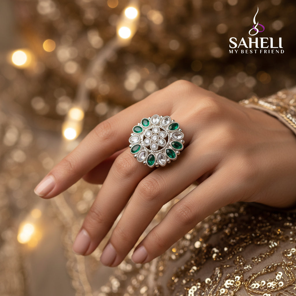 A silver-toned floral ring with green stones, displayed on a black velvet gloved hand against a black background, with the brand name 'SAHELL MY BEST FRIEND' centered above the hand.