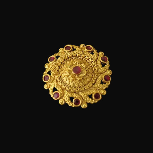 Gold ring with red gemstones on a black mannequin hand against a dark background