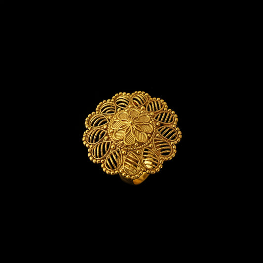 A gold filigree ring with a circular mandala-like floral design, displayed on a black hand against a dark gray background. The brand logo 'SAHELI JEWELLERY' is visible in the top left corner.