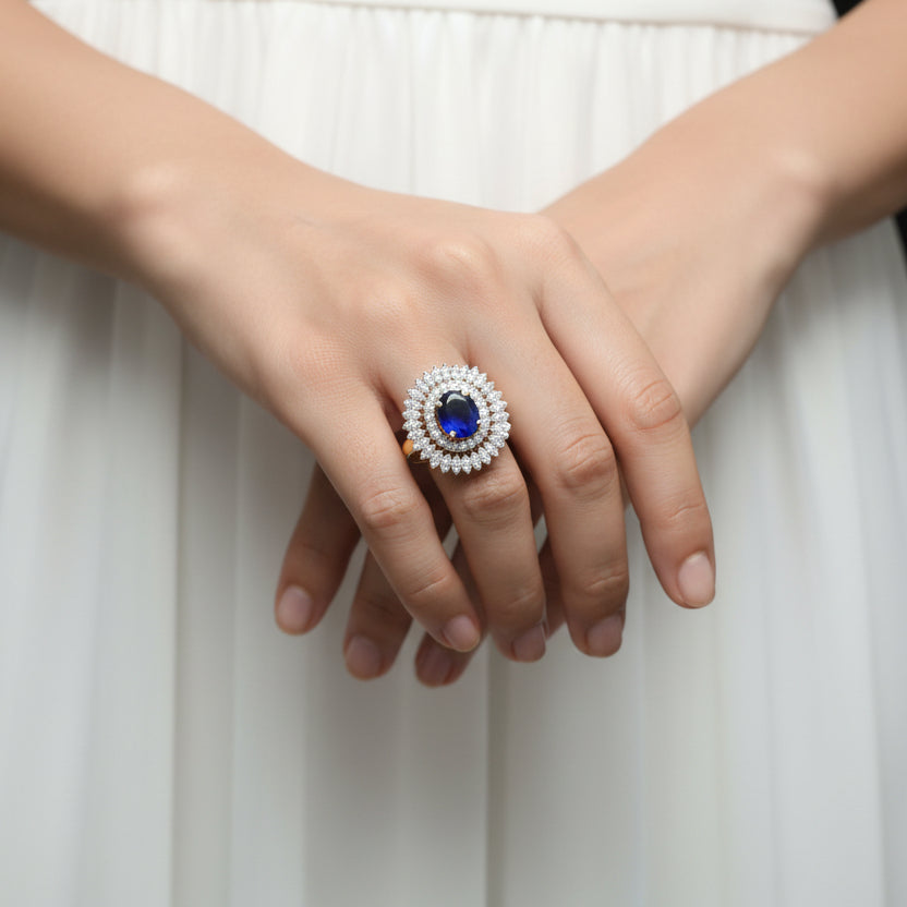 Jewelry ring with blue gemstone and diamond-like stones on a gray background, featuring the brand 'SAHELL'.