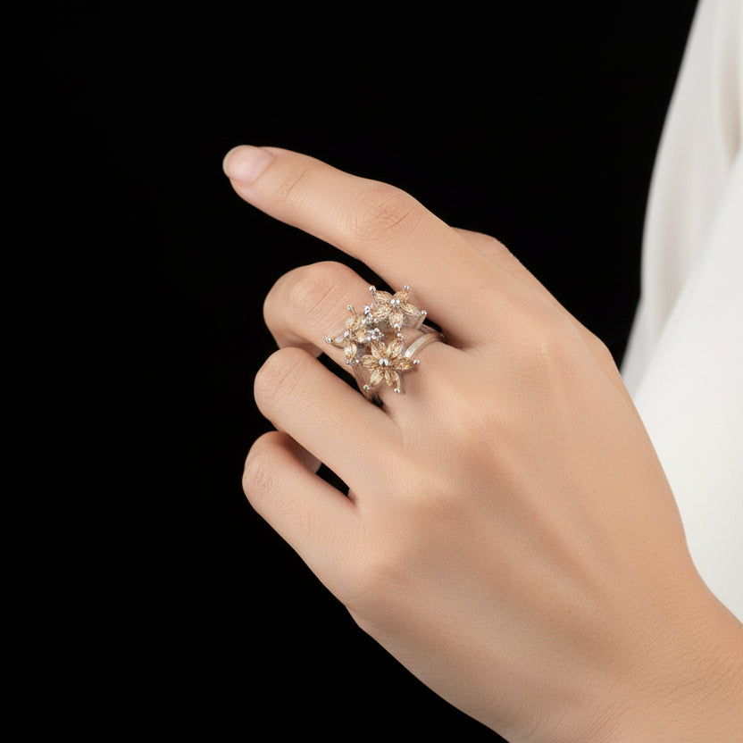 Silver ring with floral design on a gray background, featuring the brand 'Saheli'.