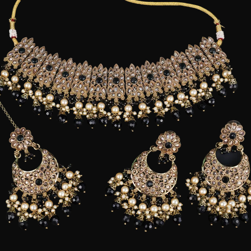 Jewelry set with necklace and earrings on a dark background, featuring the brand 'Saheli'.