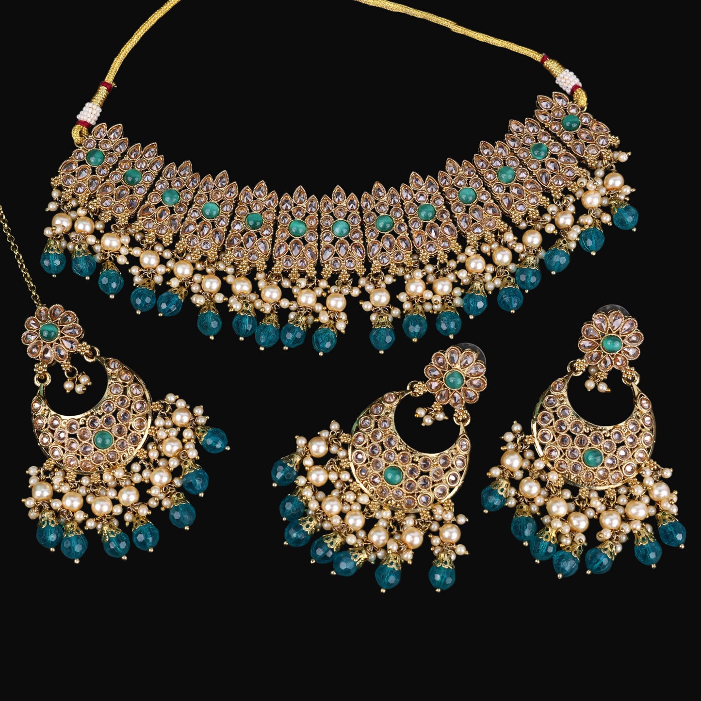 Jewelry set with necklace and earrings on a dark background, featuring brand 'Saheli'.