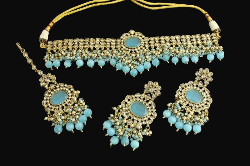 Ornate jewelry set with turquoise stones and gold accents on a dark background