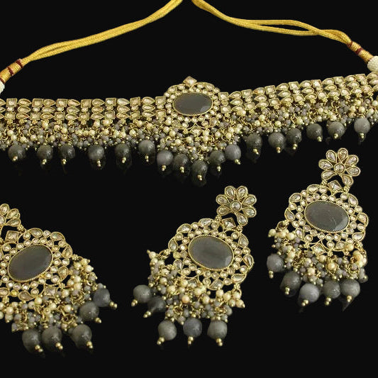 Ornate gold and gray jewelry set on a dark background