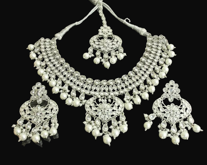 Silver necklace and earrings set on a reflective surface